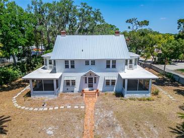 Charming two-story home with wraparound porch, lush trees, and brick path at 5603 Palmetto Rd, New Port Richey, FL 34652
