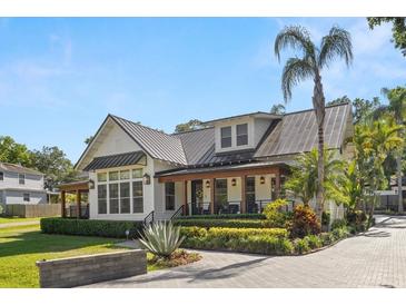 Charming two-story home featuring manicured landscaping, a metal roof, and a welcoming covered porch at 5610 N River Shore Dr, Tampa, FL 33603