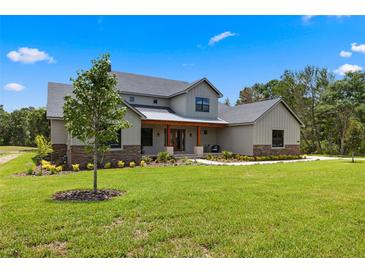 Charming two-story home featuring a landscaped front yard, stone accents, and a welcoming front porch at 5865 Creek Ridge Rd, Brooksville, FL 34601