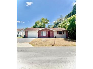 Charming single-story home with brick accents, a well-manicured lawn, and an attached garage at 7734 Judith Cres, Port Richey, FL 34668