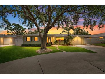Charming single-story home with a well-manicured lawn, mature tree and attached garage at sunset at 12453 138Th N St, Largo, FL 33774
