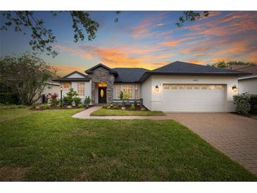 Charming home with a manicured lawn, stone accents, and a brick driveway at sunset at 14019 Nighthawk Ter, Lakewood Ranch, FL 34202
