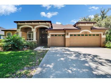 Charming, single-story home with a manicured lawn and spacious three-car garage on a sunny day at 15724 Ibisridge Dr, Lithia, FL 33547
