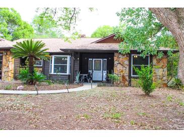 Charming stone and wood home featuring a well maintained front yard and inviting entryway at 16536 Caldwell Ln, Spring Hill, FL 34610