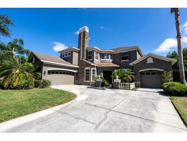 Stately home features a stone chimney, two-car garage, and circular driveway at 16637 Ashton Green Dr, Lutz, FL 33558