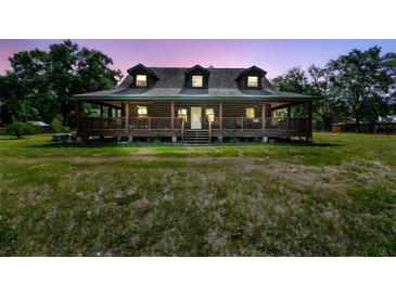 Charming log cabin with a spacious porch, nestled among mature trees, creating a serene and inviting ambiance at 19708 Bower Rd, Dade City, FL 33523