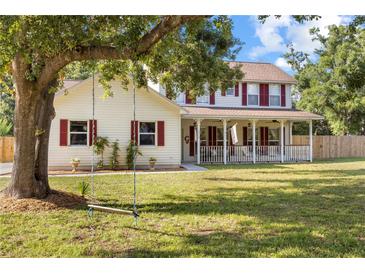 Beautiful two-story home with a large front yard featuring mature trees and a charming swing at 2512 Rustic Oaks Dr, Lutz, FL 33559