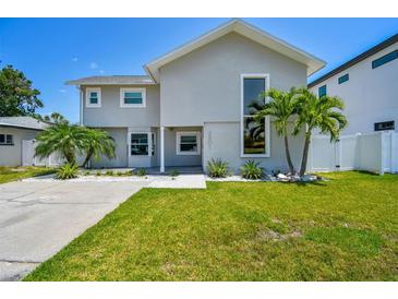 Charming two-story home featuring a well-manicured lawn, palm trees, and modern architectural details at 3801 Huntington Ne St, St Petersburg, FL 33703