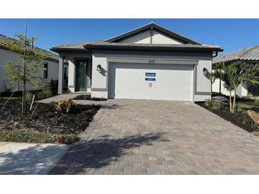 Beautiful home featuring a two-car garage, a paved driveway, and lush landscaping at 6137 Wire Grass Ct, Nokomis, FL 34275