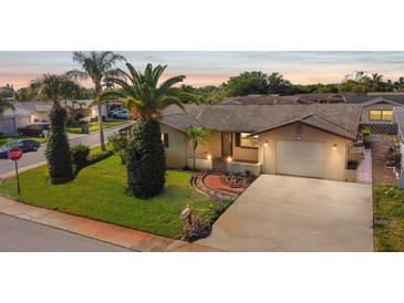 Charming single-story home featuring a well-manicured lawn, mature landscaping, and a driveway leading to an attached garage at 7534 Culberson Dr, Port Richey, FL 34668