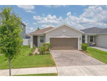 Charming single-story home featuring a well-manicured lawn, lush landscaping, and a brick-paved driveway at 11830 Brighton Knoll Loop, Riverview, FL 33579