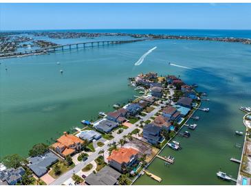 Stunning aerial view of waterfront homes, featuring boat docks and clear blue water in the distance at 14 Sunset Bay Dr, Belleair, FL 33756
