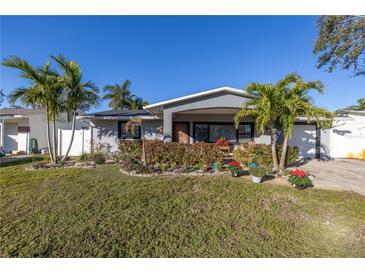 Charming single-story home with a well-manicured lawn and lush landscaping, including palm trees at 1990 59Th N St, St Petersburg, FL 33710