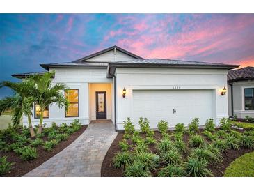 Charming single-story home with a well-manicured lawn, paved walkway, and a two-car garage at 6017 Silver Grass Ct, Nokomis, FL 34275