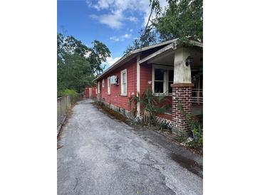 Red home exterior showing side yard and driveway under a blue sky at 7807 N Mulberry St, Tampa, FL 33604