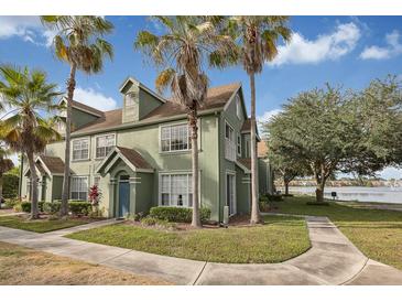 Inviting townhome featuring lush landscaping, a blue front door, and serene water views at 9414 Lake Chase Island Way # 9414, Tampa, FL 33626