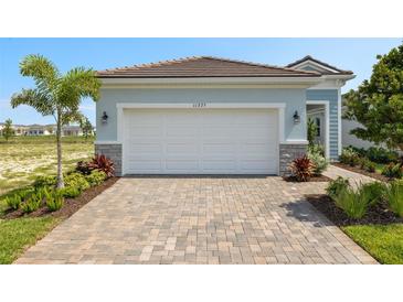 Garage and patterned driveway in front of a two-car garage with manicured landscaping at 11375 Boundless Ter, Venice, FL 34293