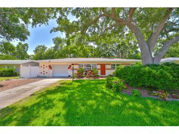 Charming single-story home with a lush green lawn, mature trees, and a cozy, inviting exterior at 1500 Robinson N Dr, St Petersburg, FL 33710