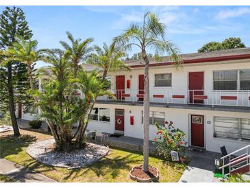 Charming condo featuring red entry doors, tropical landscaping, and well-maintained grounds at 1900 58Th N Ave # 26, St Petersburg, FL 33714