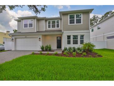 Charming two-story home featuring manicured lawn, fresh landscaping, and a light gray color palette at 3614 W Platt St, Tampa, FL 33609