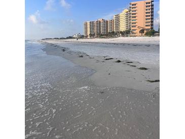 Expansive beachfront view with pristine white sand and luxury condominiums in the background at 880 Mandalay Ave # S302, Clearwater Beach, FL 33767