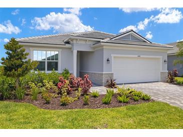 Charming home with a well-manicured front yard, a paver driveway, and a two-car garage at 11470 Myakka Blue Dr, Venice, FL 34293