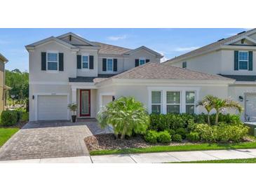 Beautiful two-story home featuring a well-manicured lawn, lush landscaping, and a charming red door at 18017 Ramble On Way, Land O Lakes, FL 34638