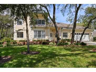 Charming two-story home with a well-manicured lawn and lovely landscaping in front at 2175 Oak Forest Ln, Palm Harbor, FL 34683