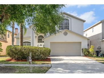 Charming two-story home featuring a two-car garage, arched windows, and mature landscaping at 27330 Coral Springs Dr, Wesley Chapel, FL 33544
