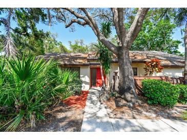 Charming single-story home featuring mature landscaping and a vibrant red front door at 2953 Yucca Ct, Palm Harbor, FL 34684