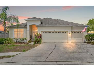 Inviting one-story home featuring a three-car garage, lush landscaping, and a well-manicured lawn at 4214 Canongate Ct, Spring Hill, FL 34609