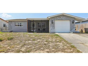 Charming home with a screen-enclosed front porch, stone accents, a single-car garage and modest landscaping at 8330 Moulton Dr, Port Richey, FL 34668