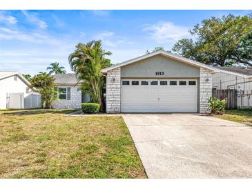 Charming single-story home with a two-car garage, brick facade, and well-maintained lawn at 1913 Peppertree Dr, Oldsmar, FL 34677