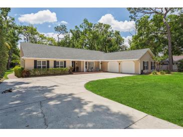 Inviting single-story home with mature trees, a large driveway, and a well-manicured lawn at 3906 Floyd Rd, Tampa, FL 33618