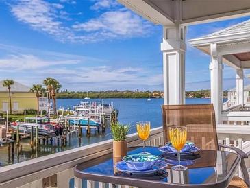 Balcony view with seating, two glasses of orange juice, and boat docks in the background at 5191 Salmon Se Dr # C, St Petersburg, FL 33705