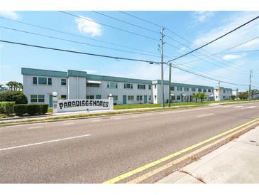 Paradise Shores condo complex featuring a welcoming sign, manicured landscaping, and a sunny day at 5356 81St N St # 26, St Petersburg, FL 33709