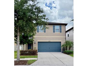 Charming two-story home featuring a blue garage door and shuttered windows at 6325 Yellow Buckeye Dr, Riverview, FL 33578