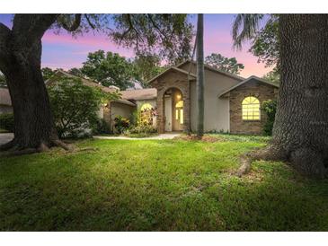 Charming single-story home featuring a brick archway, lush lawn, and mature trees at 3001 Folklore Dr, Valrico, FL 33596