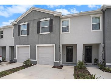 Charming gray two-story townhome featuring an attached garage and inviting front entrance at 32803 Pez Landing Ln, Wesley Chapel, FL 33543