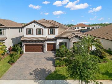 Stunning two-story home with a tile roof, a paved driveway, a manicured lawn, and a three-car garage at 5043 Night Star Trl, Odessa, FL 33556