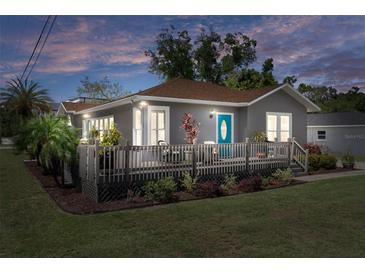 Charming home boasts a inviting front deck, complemented by well-manicured landscaping and a vibrant blue front door at 1209 W Adalee St, Tampa, FL 33603