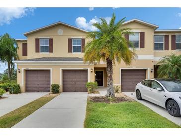 Townhomes with brown shutters, a garage and a well manicured green lawn with a palm tree at 12952 Utopia Gardens Way, Riverview, FL 33579
