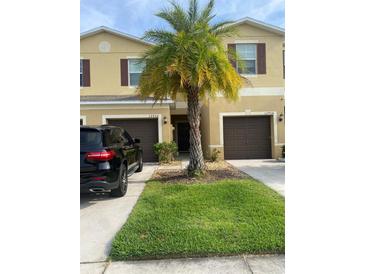 Inviting townhouse with a well-manicured lawn and a decorative palm tree in the front yard at 12952 Utopia Gardens Way, Riverview, FL 33579
