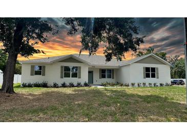 Charming single story home featuring a brick facade, dark green shutters, manicured landscaping and a warm sunset sky at 13532 14Th St, Dade City, FL 33525