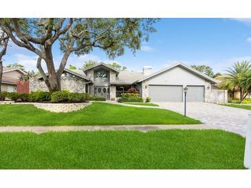 Charming single-story home with stone accents, a well-manicured lawn, and an attached two-car garage at 3342 Waterford Dr, Clearwater, FL 33761