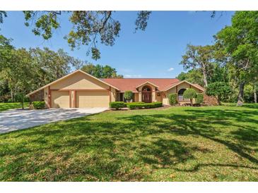 Charming single-story home with a three-car garage, well-maintained lawn, and mature trees at 7353 Dogwood Cres, Spring Hill, FL 34607
