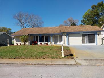 Charming single-story home featuring a well-manicured lawn, attached garage, and covered porch at 8313 Cavalry Dr, Hudson, FL 34667