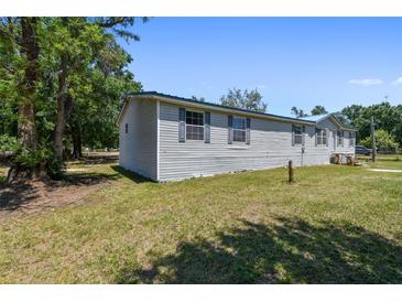 Well-maintained home with a light gray exterior, complemented by lush trees and a green lawn at 12502 Tocci Ln, Riverview, FL 33579