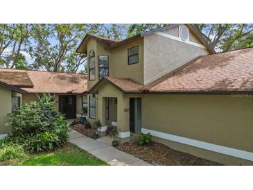 Charming two-story home with neutral stucco, well-manicured landscaping, and inviting front porch at 1693 Fry Ct, Dunedin, FL 34698