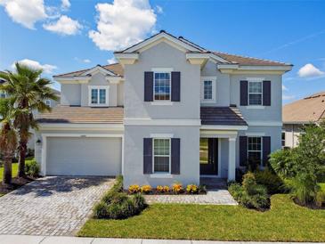 Beautiful two-story home featuring manicured lawn, neutral exterior, and paver driveway at 34084 Torrent Ln, Wesley Chapel, FL 33543